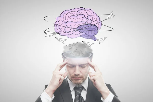 Hombre de negocios pensativo con esbozo de cerebro abstracto sobre fondo claro. Concepto de lluvia de ideas — Foto de Stock