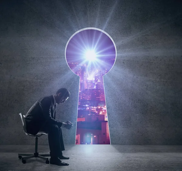 Vue latérale d'un jeune homme d'affaires réfléchi assis sur une chaise à l'intérieur avec ouverture de trou de serrure révélant une vue nocturne sur la ville. Concept de réussite . — Photo