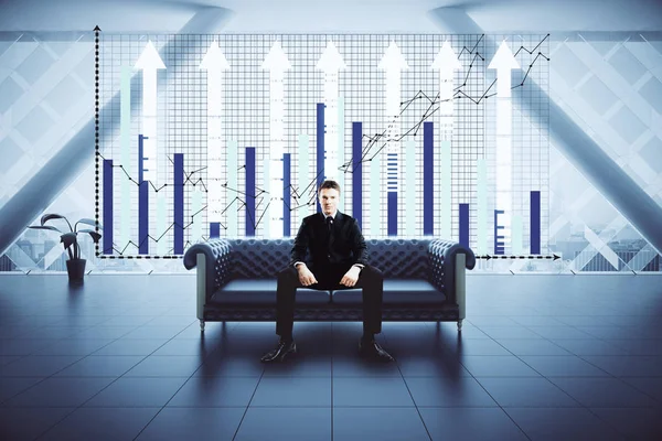 Businessman sitting on sofa in interior with city view and business chart. Finance concept. — Stock Photo, Image