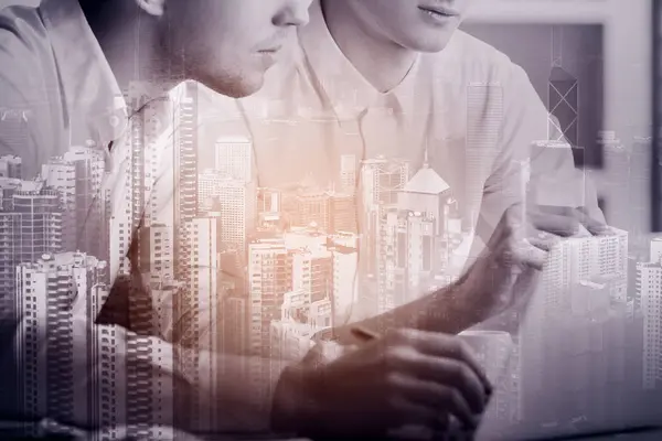 Dos hombres de negocios guapos usando portátil sobre fondo abstracto de la ciudad. Imagen filtrada. Concepto de trabajo en equipo . —  Fotos de Stock