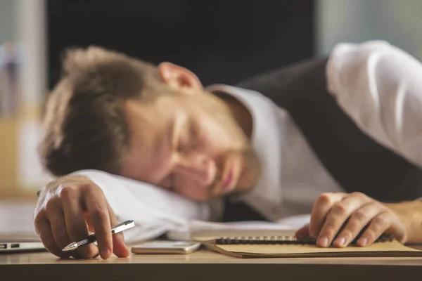 Schöner junger europäischer Geschäftsmann, der auf seinem Schreibtisch schläft. Überarbeitetes Konzept — Stockfoto