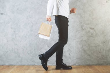 Adamın bacakları ve boş alışveriş çantası elinde beton duvar ve ahşap zemin ile odada yan görünüm. Satınalma kavramı. Yukarı alay