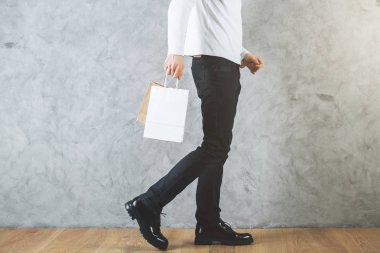 Adamın bacakları ve boş alışveriş çantası elinde beton duvar ve ahşap zemin ile odada yan görünüm. Perakende kavramı.