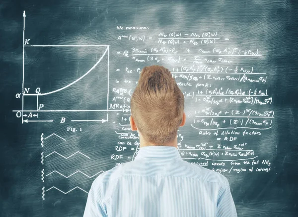 Achteraanzicht van jonge zakenman met vragen kijken schoolbord met wiskundige formules. Kennis concept — Stockfoto