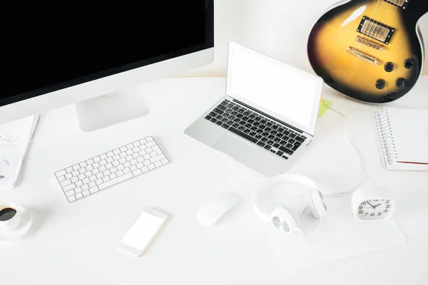 Pohled shora zářivě bílý stůl s laptop, počítač, smartphone, klávesnice, sluchátka, kytara a další položky. Hudební koncept. Vysmívat se — Stock fotografie