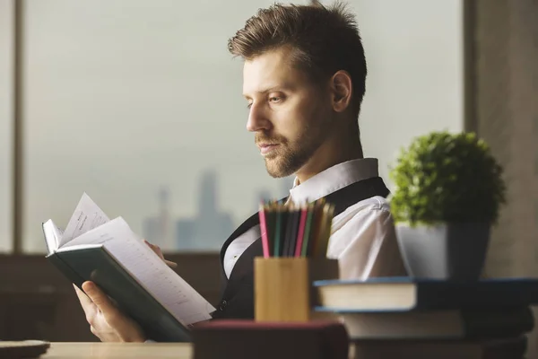 Portrait de beau jeune homme d'affaires lisant le livre sur le lieu de travail de bureau moderne. Concept de littérature — Photo