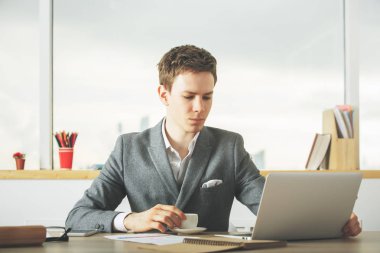 Erkek işçi içme kahve dizüstü bilgisayar kullanarak 