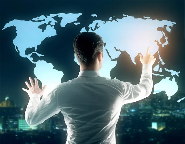 Vista posterior de un joven hombre de negocios tocando el mapa del mundo en el fondo borroso de la ciudad nocturna. Concepto futuro —  Fotos de Stock