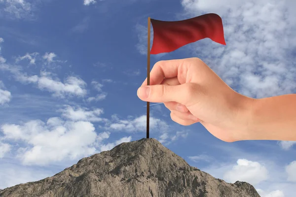 山の頂上に手を振っている赤い旗を配置する手。空の背景。勝つ概念 — ストック写真