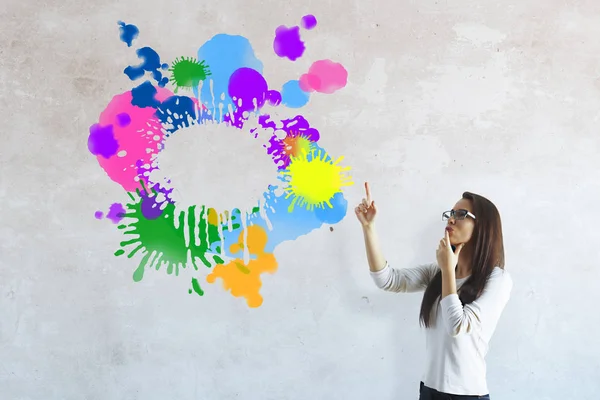Doordachte jonge vrouw wijzend op abstract kleurrijk schets op betonnen muur. Brainstorm concept — Stockfoto