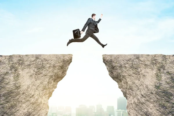 Side view of businessman jumping from cliff to cliff on bright city background. Risk concept — Stock Photo, Image