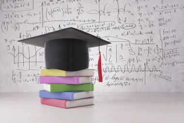 Soyut mezuniyet şapka ve renkli kitap yığın beton yüzeyine yerleştirilir. Duvar arka planda matematiksel formüller ile. Mezuniyet kavramı. 3D render 