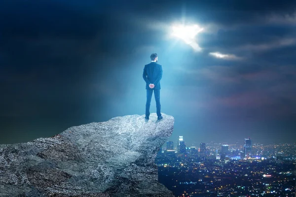 Vista trasera de un joven hombre de negocios en la cima de la montaña mirando la ciudad nocturna con luz de luna. Concepto de empleo. Copiar espacio — Foto de Stock