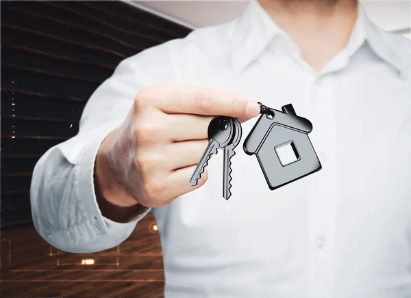 Businessman holding key with house keychain in modern interior. Mortgage concept. 3D Rendering — Stock Photo, Image
