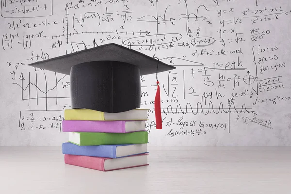 Abstrakte Graduiertenmütze und bunte Bücherstapel auf Betonoberfläche platziert. Wand mit mathematischen Formeln im Hintergrund. Abschluss-Konzept. 3D-Darstellung — Stockfoto