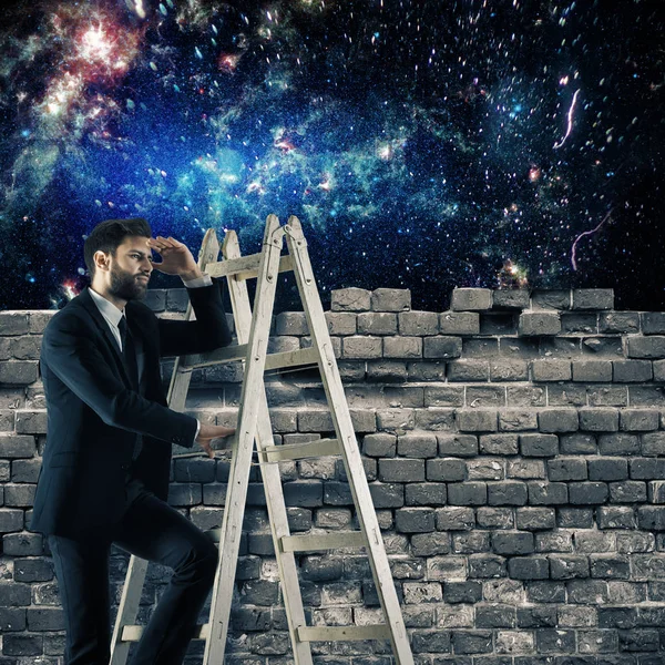 レンガの壁の後ろから宇宙を見ての梯子の上の青年実業家。概念冒険 — ストック写真