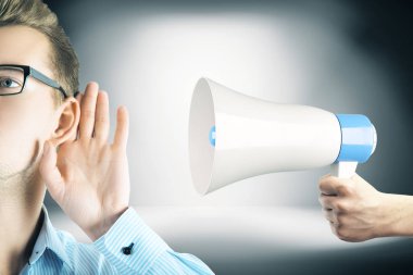 Hoparlör duyuru, gri gradyan arka taraftan tarafından tutulan dinlerken yakışıklı delikanlı. İletişim kavramı 