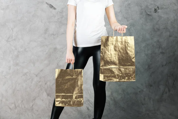 Закрыть женщину с пустыми глянцевыми бумажными пакетами для покупок на бетонном фоне. Экологическая концепция. Mock up — стоковое фото