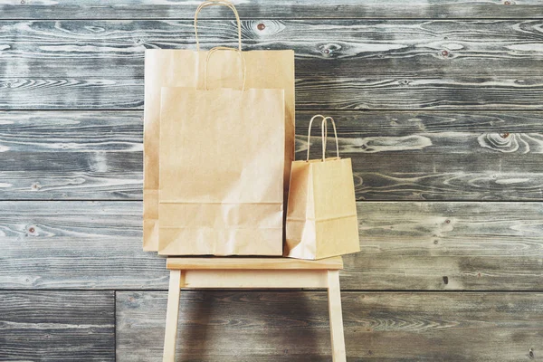 Bolsas de compras de papel marrón vacías colocadas en la escalera. Fondo de pared de tablón de madera. Concepto publicitario. Prepárate. — Foto de Stock
