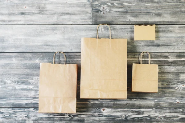 Sacos de compras de papel marrom em branco pendurados na parede de madeira. Conceito reciclável. Faz asneira. — Fotografia de Stock