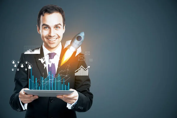 Hombre de negocios sonriente sosteniendo la tableta con holograma de pantalla de negocios y lanzamiento de cohetes. Concepto de emprendimiento —  Fotos de Stock