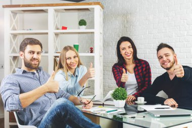 Çekici genç beyaz iş erkek ve cihazlarla, evrak Ofis Masası oturma ve başparmak gösteren kadın. Başarı kavramı 