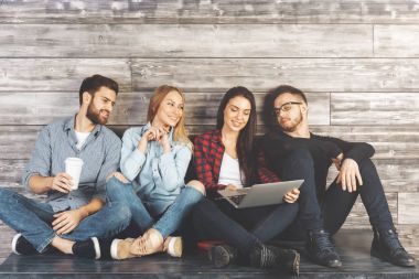 Ahşap duvar ile modern ofis masasında bakimi, öğeleri elinde tutan ve having fun genç Avrupa ekip üyeleri. İşbirliği kavramı 