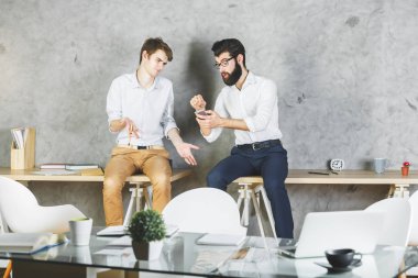 Masada oturan ve having fun birlikte modern ofiste iki yakışıklı iş adamları. Sonu kavramı 