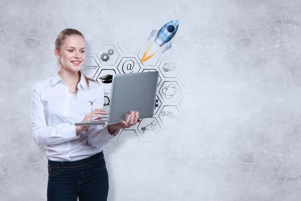 Joyeux jeune femme européenne en utilisant un ordinateur portable sur fond de mur en béton avec esquisse d'affaires créative. Concept d'esprit d'entreprise — Photo