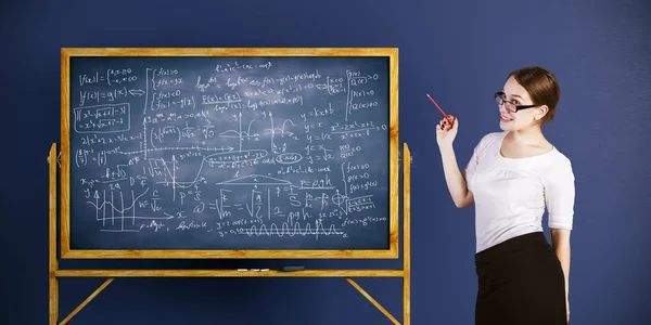 Mujer de negocios sonriente de pie junto a pizarra con fórmulas matemáticas sobre fondo de pared azul. Concepto de tutor. Renderizado 3D — Foto de Stock