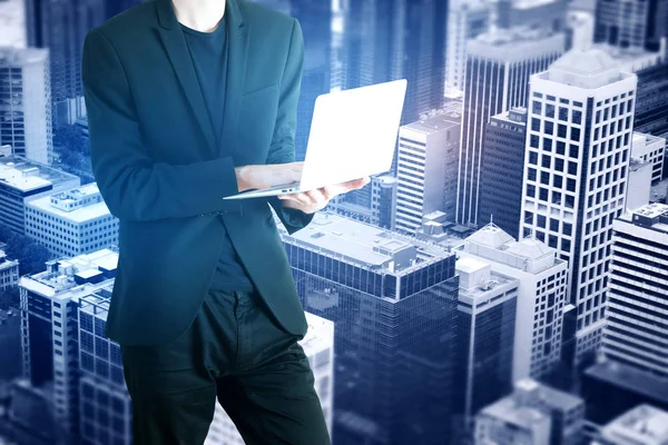Uomo d'affari che utilizza computer portatile su astratto sfondo blu della città con spazio di copia. Concetto di comunicazione — Foto Stock