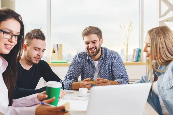 Attraktive junge europäische Gruppe, Geschäftsleute und -frauen, die an Projekten im modernen Büro mit Laptop, Smartphone, Papierkram und anderen Dingen auf dem Schreibtisch arbeiten. Arbeitsplatzkonzept — Stockfoto