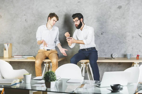 Masada oturan ve having fun birlikte modern ofiste iki yakışıklı iş adamları. Sonu kavramı 