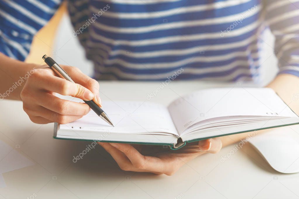 Woman writing in hardcover diary