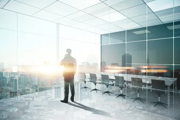 Vista trasera del joven hombre de negocios hablando por teléfono en el interior de la sala de conferencias moderna con vista a la ciudad y la luz del sol. Concepto de comunicación. Doble exposición —  Fotos de Stock