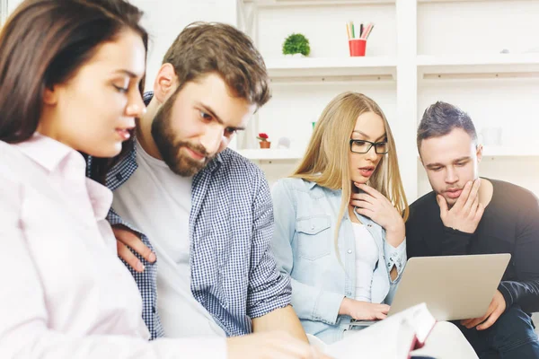 Ungdomar i moderna office använder bärbar dator och diskuterar något. Arbetskonceptet — Stockfoto