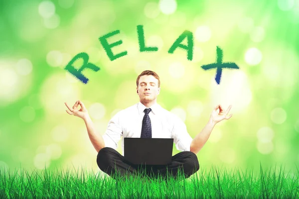 Atraktivní mladý podnikatel s notebookem meditaci na pozadí rozmazané zelené trávy. Relax koncept — Stock fotografie