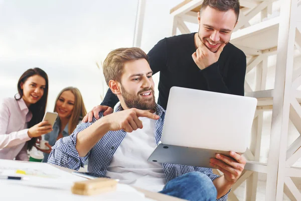 Attraktive junge europäische Gruppe, Geschäftsleute und -frauen, die an Projekten im modernen Büro mit Laptop, Smartphone, Papierkram und anderen Dingen auf dem Schreibtisch arbeiten. Unternehmer-Konzept — Stockfoto