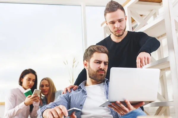 Attraktive junge europäische Gruppe, Geschäftsleute und -frauen, die an Projekten im modernen Büro mit Laptop, Smartphone, Papierkram und anderen Dingen auf dem Schreibtisch arbeiten. Unternehmerisches Konzept — Stockfoto