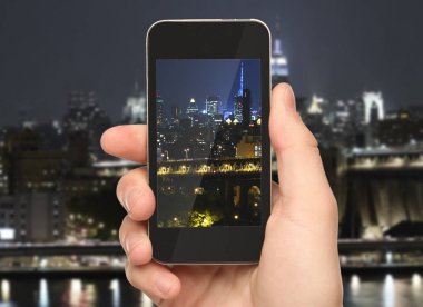 Akıllı telefon ışıklı gece şehir arka planda tutan el. Kentsel kavramı 