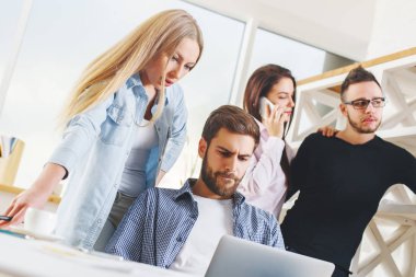 Çekici genç Avrupa grubu, iş erkek ve kadın modern ofis dizüstü, smartphone, evrak ve diğer öğeleri üstünde okul sırası ile proje üzerinde. Beyin fırtınası kavramı 