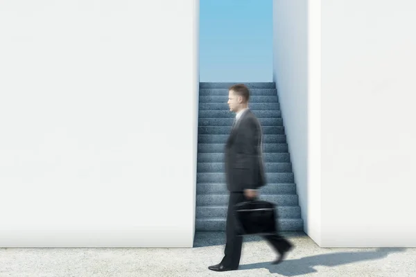 Vista lateral de un joven hombre de negocios borroso que pasa por las escaleras con vista al cielo y copia el espacio en la pared. Concepto de avance. Maquillaje, renderizado 3D — Foto de Stock