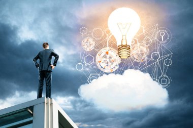 Bulut, iş hologram ve parlayan laptop ile gökyüzüne bakarak çatıda arkadan görünüm genç işadamı. İnovasyon kavramı 