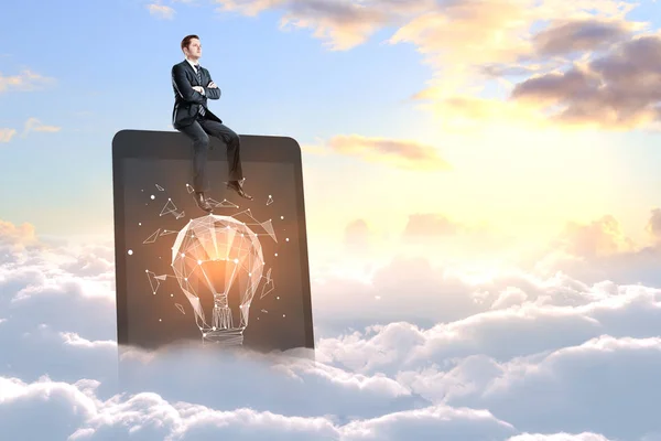 Businessman sitting on laptop with polygonal lamp on screen in sky with clouds. Imagination concept — Stock Photo, Image