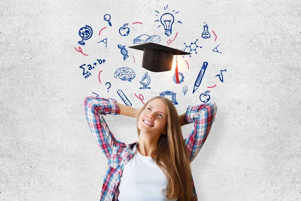 Vrolijke jonge vrouw stond op betonnen muur achtergrond met mortarboard en educatieve schets. Kennis concept — Stockfoto