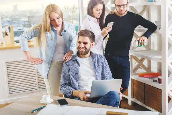 Attractive young european group, business men and women working on project in modern office with laptop, smartphone, paperwork and other items on desk. Collaboration concept — Stock Photo, Image