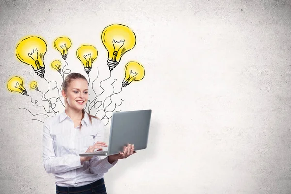 Lächelnde junge Geschäftsfrau mit Laptop auf Betonwandhintergrund mit Glühbirnenskizze. Ideenkonzept — Stockfoto