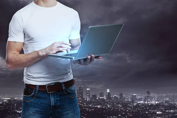 Unerkennbarer Mann mit Laptop auf nächtlichem Stadthintergrund. Netzwerkkonzept — Stockfoto