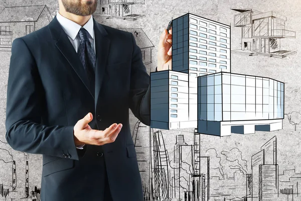 Empresario sosteniendo boceto abstracto del edificio en el fondo concreto. Concepto hipotecario — Foto de Stock