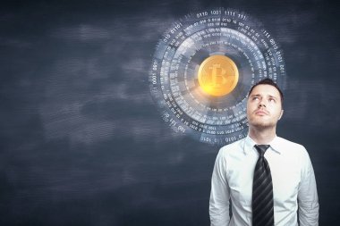 Kara tahta duvar arka plan kopya alanı ve bitcoin hologram ile üzerinde duran düşünceli genç işadamı portresi. Cryptocurrency kavramı 